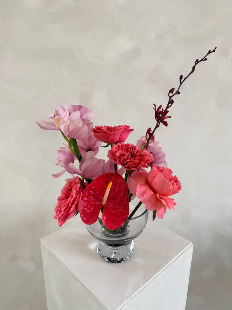 Floral centerpiece with orchids, roses and anthurium in a glass vase